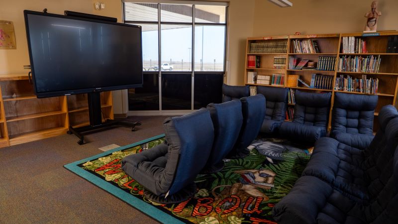 Inside the school library, there’s a big screen and comfy chairs arranged for students to use.