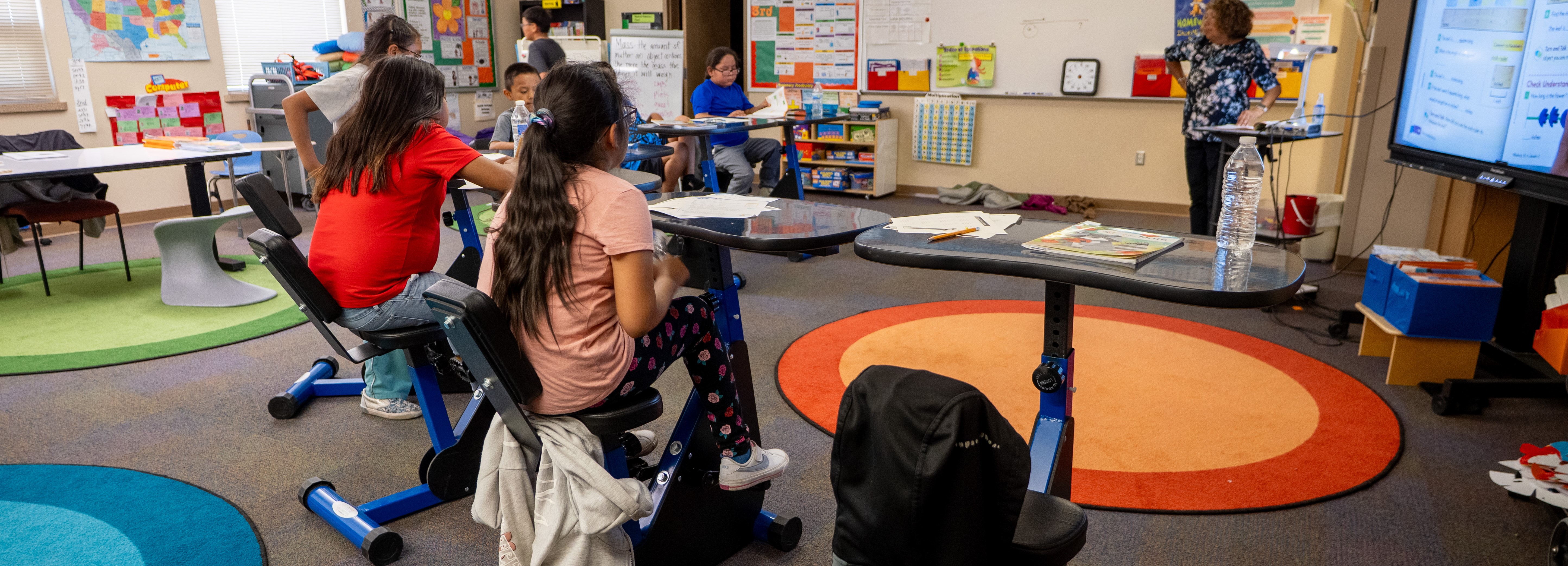 A classroom filled with students riding exercise bikes, combining physical activity with their studies.